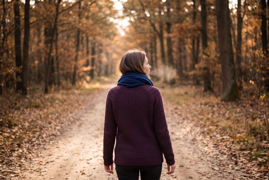 Frau geht ruhig durch einen herbstlichen Waldweg – langfristige Entspannung